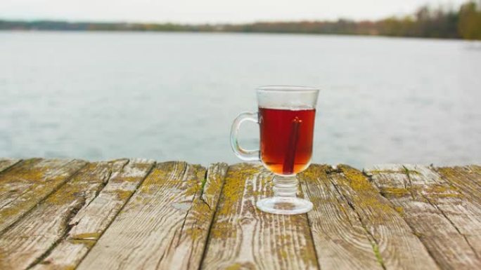 爱尔兰玻璃杯里装满了旧木皮上的茶。女人的手把西那蒙棒放进玻璃杯里。