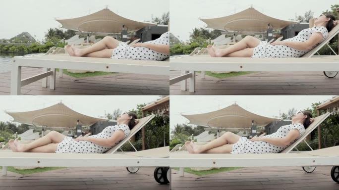 快乐的亚洲女人在度假期间在酒店的日光浴床上放松，生活方式理念。