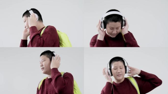 亚洲男生穿着红色毛衣跳舞唱歌，同时在灰色背景上使用无线耳机，生活方式概念。