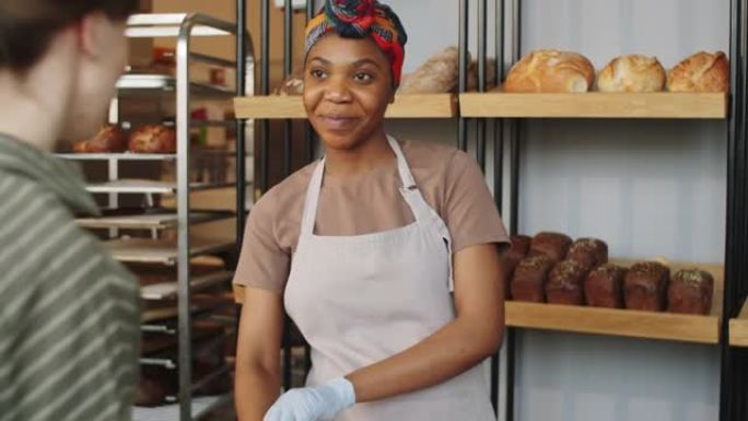 美丽的黑人妇女在面包店卖新鲜面包