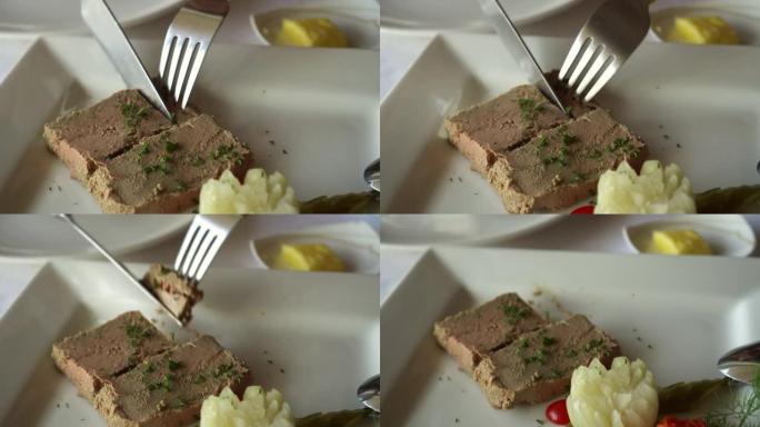 法国餐厅的刀叉切鹅肝开胃菜，咸菜和土豆泥