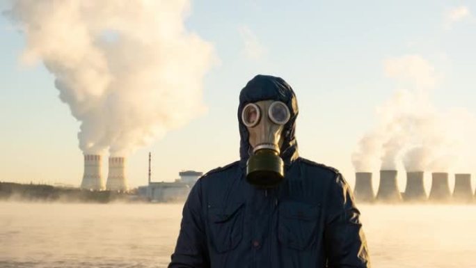 核电站的延时发电厂将化学物质释放到大气中。一个人戴着防毒面具站着。储液罐蒸发了。全球变暖和辐射