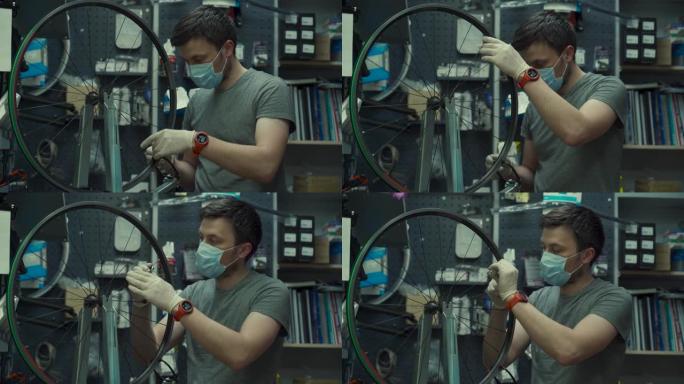 自行车店修理工在自行车服务和维修车间工作，在冠状病毒检疫戴着面罩和手套，这是新的规范。机械修理自行车