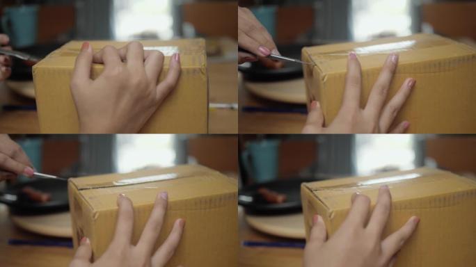 孩子的手用切割器打开棕色包裹箱，这是从网上家庭购物购买的，生活方式概念。