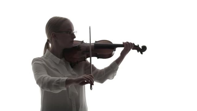 穿着衬衫的女音乐家在白色背景的工作室里用蝴蝶结拉小提琴。金发小提琴手拉小提琴