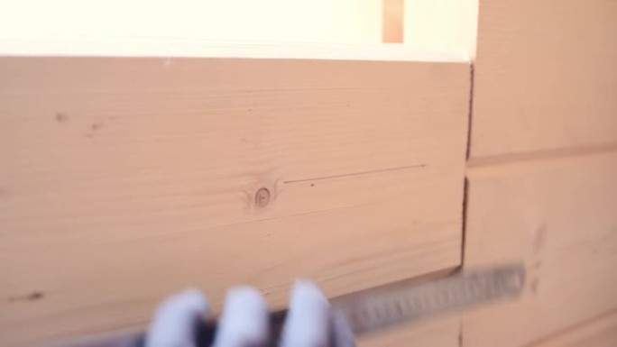 戴着手套的工人用钢尺和铅笔在木墙上打上标记