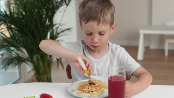 厨房里的男孩在家里吃意大利面时微笑着。好孩子食欲概念