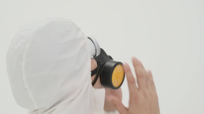 穿着防护服的男人给自己戴上防毒面具的特写镜头。以白色背景拍摄。