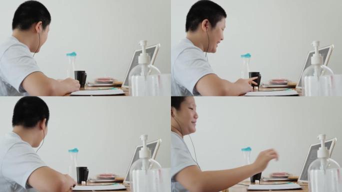 亚洲男孩在新型冠状病毒肺炎期间通过数字平板电脑在家在线学习，社交距离生活方式概念。
