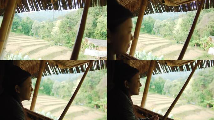 亚洲女性旅行者在山脉背景上的热带森林中打开度假寄宿家庭的窗户。自然旅行的概念。4k慢动作。