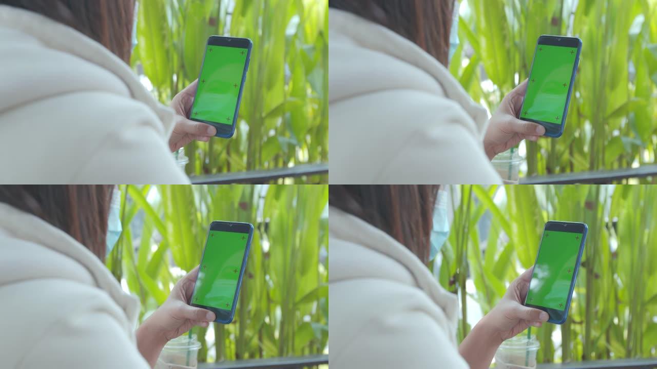 关闭女人手里拿着智能手机，色键绿色屏幕在咖啡馆。