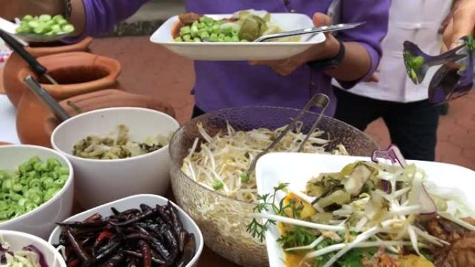 午餐休息教育人们和学生在泰国传统服装排队等待食物饭或米粉蔬菜泰国北方风格。户外餐饮餐饮派对理念。