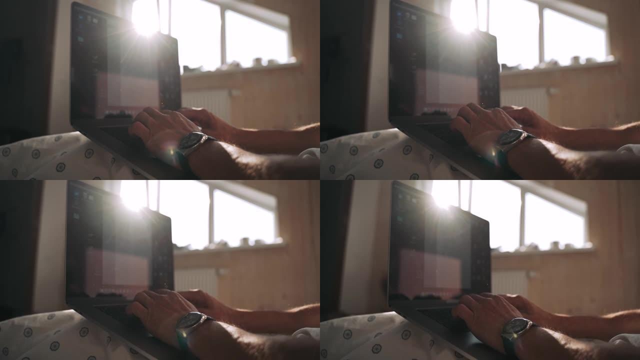 男人的手在笔记本电脑上打字美丽的阳光从窗户落下日落的阴影躺在床上，员工正在计算机上慢动作