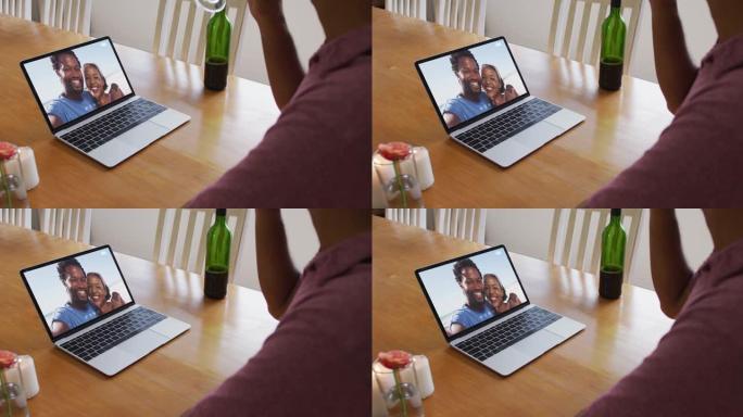 非裔美国人的中间部分在家里用笔记本电脑进行视频通话时喝酒
