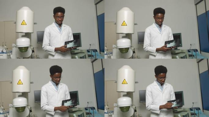 拿着数字平板电脑的医生。微笑的非洲男子医生的特写肖像，站在超声波和碎石机前。安全无创结石治疗