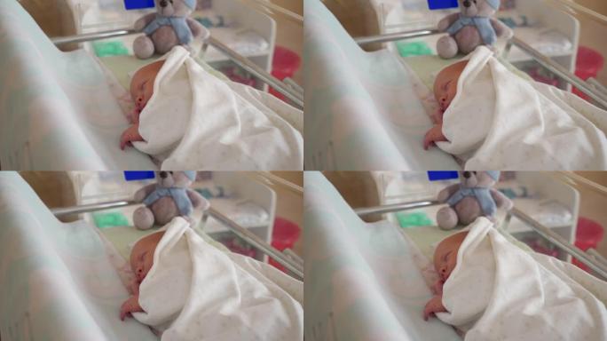 新生儿男婴躺在妇产医院的婴儿床里，婴儿正在睡觉