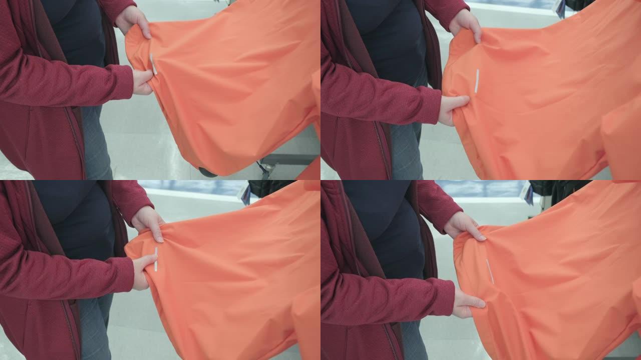 孕妇在商店选择带反光条纹的橙色夹克购买