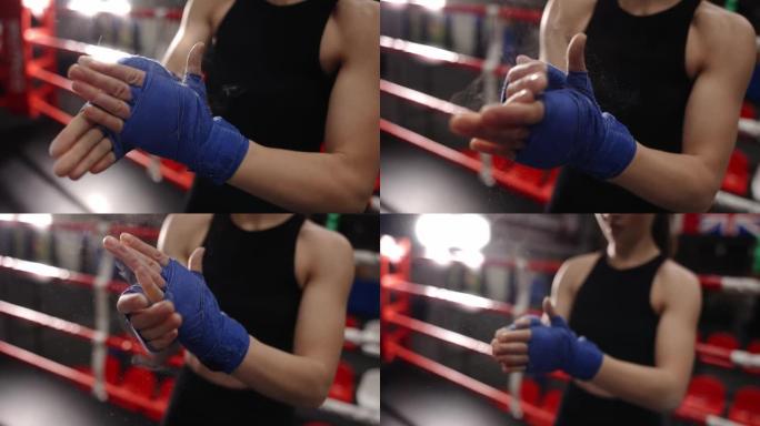 女人在拳击台上用拳击胶带包裹的手上摩擦粉末