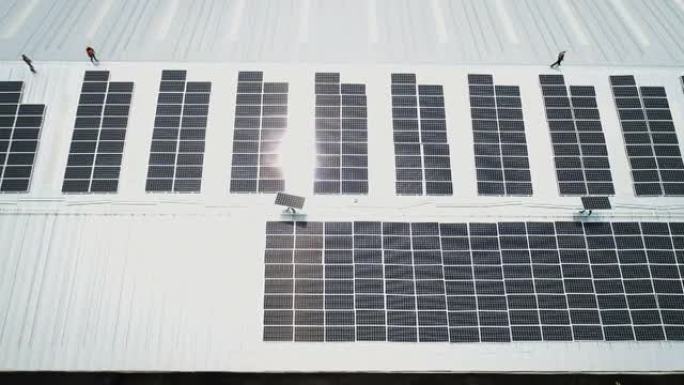 在工厂屋顶上安装太阳能电池板的工人团队