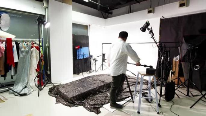 摄影师在延时拍摄中设置了带照明设备背景的工作室