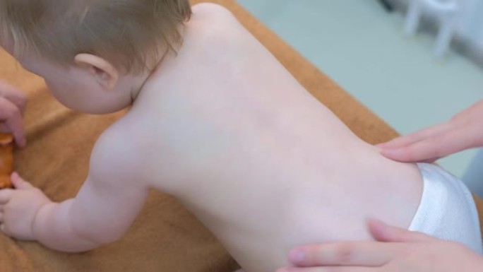 专业医生按摩师在诊所对婴儿背部脊柱进行按摩。