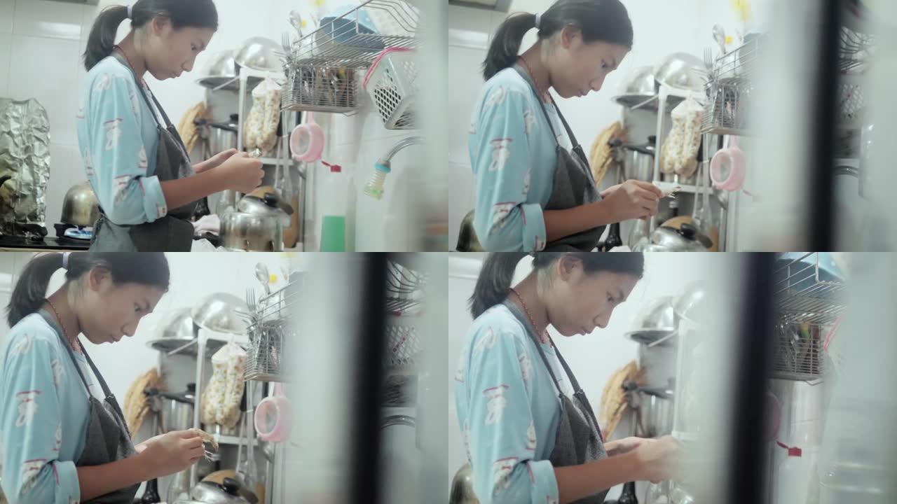 亚洲女孩穿着围裙脱皮，在厨房里为烹饪前准备食物去皮虾，生活方式理念。