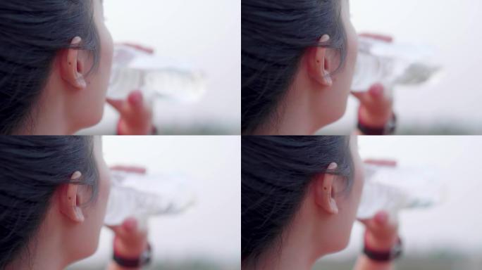 年轻的运动亚洲妇女在完成户外运动后喝淡水