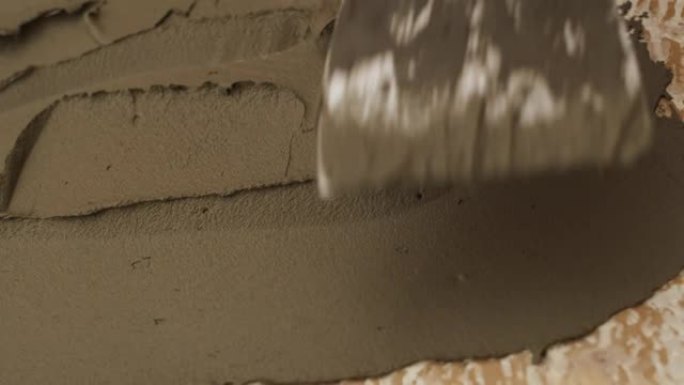 泥水匠用抹刀涂抹瓷砖砂浆。男性手用抹刀涂抹石膏