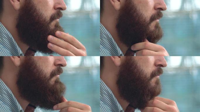 特写大胡子男人抚摸胡须并思考的镜头。