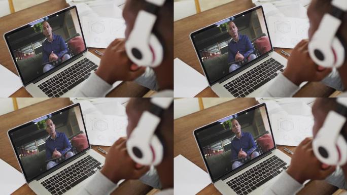 非裔美国商人坐在办公桌前，使用笔记本电脑与男同事进行视频通话