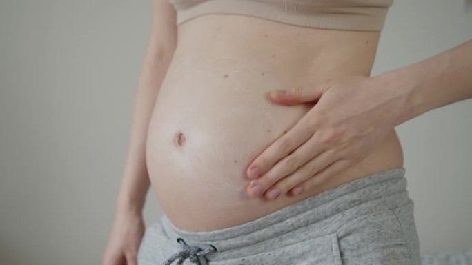 年轻孕妇在腹部涂抹妊娠纹按摩乳液