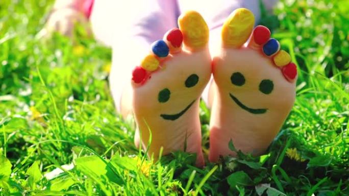 孩子的脚在草地上夏天画的微笑。选择性聚焦。孩子。