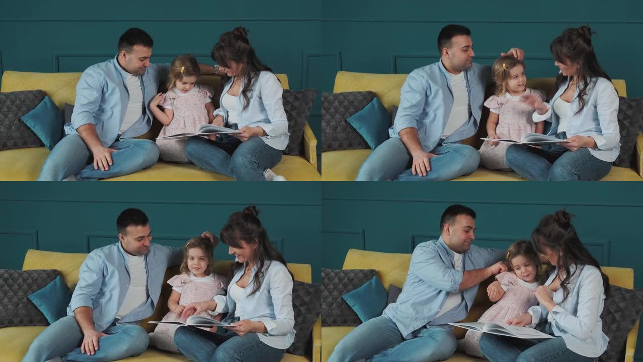年轻的家庭坐在沙发上给小女儿读书
