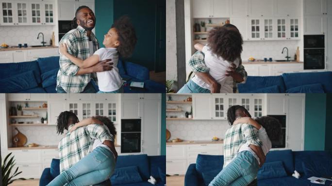 快乐的非洲裔美国父亲抓住他的小女儿，抱起她，扭来扭去，慢动作