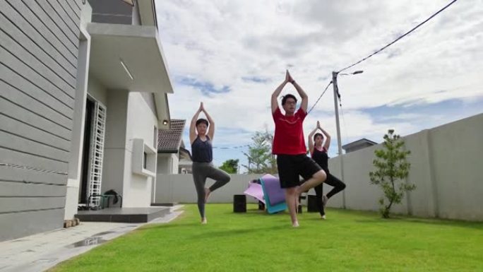 一群亚洲华人朋友练习瑜伽的房子早上的前院
