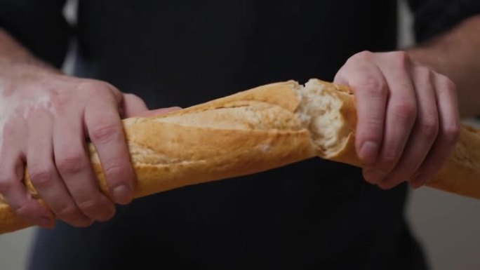 特写有机美味法式长棍面包在背景上的一个男人手中