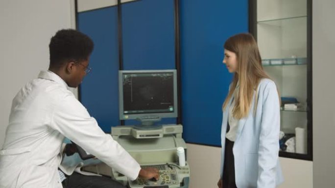 现代诊所的非裔美国家庭医生，拿着平板电脑向女性高加索患者展示肾脏和内脏的超声扫描并解释治疗方法