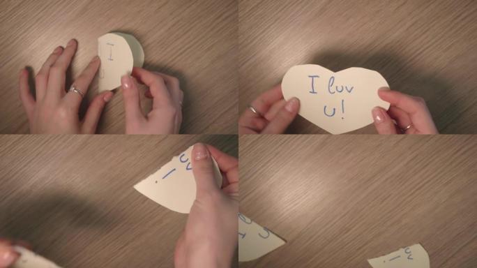 女孩的手拿一个心形的纸条，写着我喜欢你打开它，撕成两部分。