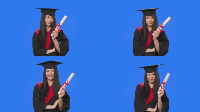 穿着毕业服装的女学生的肖像若有所思地看着她的文凭，然后高兴地有一个想法。年轻女子在蓝屏背景上摆姿势。