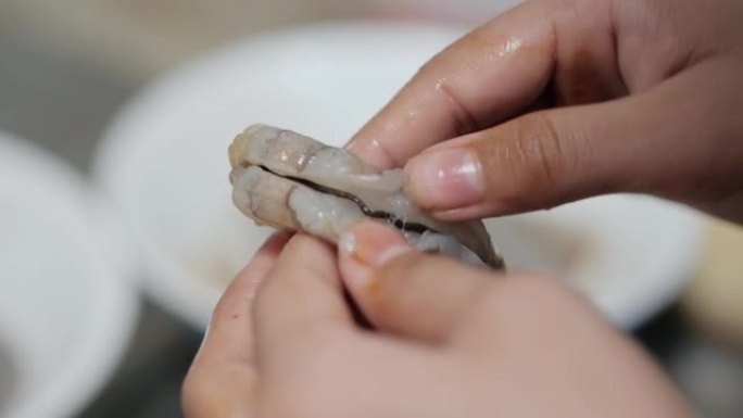 儿童在厨房里用手剥皮和去皮虾做饭前准备食物，生活方式的概念。