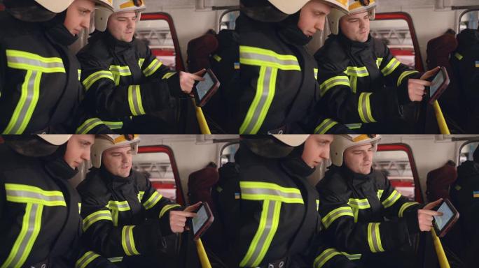 两名消防员在卡车机舱的数字平板电脑上分析数据