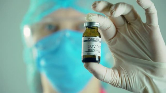 医生微生物学家病毒学研究人员在实验室戴着防护口罩和手套拿着安瓿注射疫苗