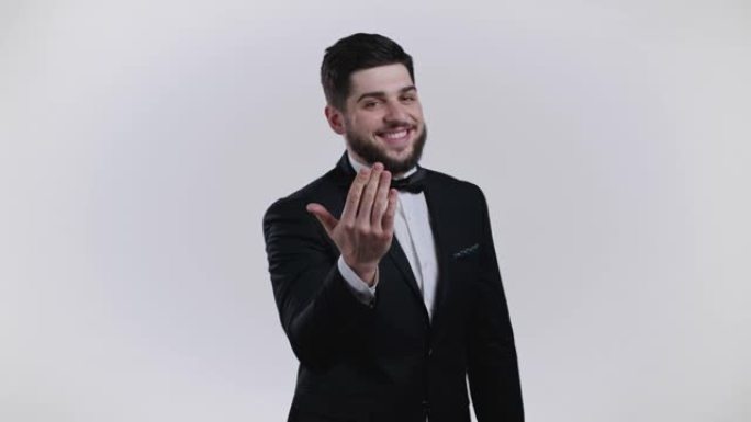 穿着燕尾服的帅哥展示-嘿，你，过来。表演者问加入他，以诱人的姿态招手。他看起来很顽皮，很招人来。白色
