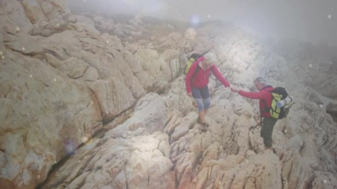 快乐的高加索高级夫妇手牵着手在岩石上徒步旅行，越过掉落的bokeh光点