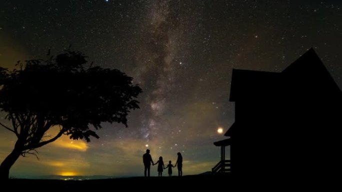 一家人站在星空背景上的房子附近