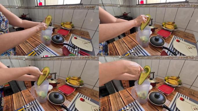 女性手将鳄梨的果肉放入搅拌机的个人观点