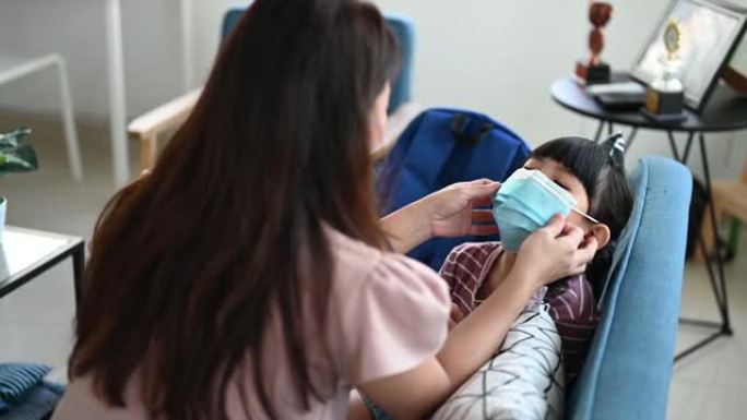 亚洲母亲帮助女儿戴上口罩保护新冠肺炎疫情