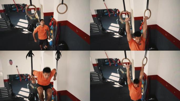 一名年轻的运动男子在健身房的体操环上锻炼