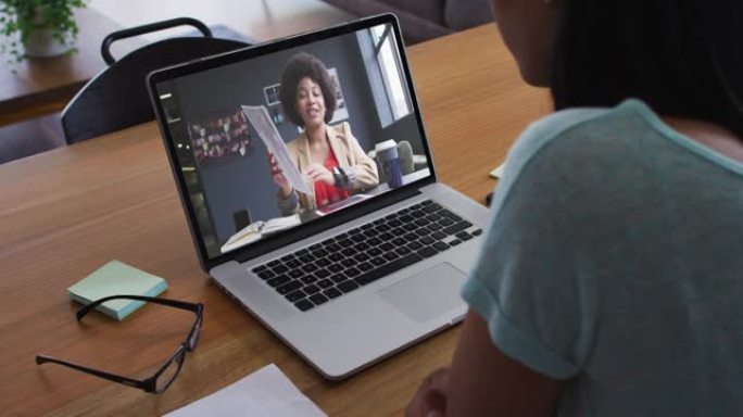 非裔美国妇女在家里的笔记本电脑上与女办公室同事进行视频通话