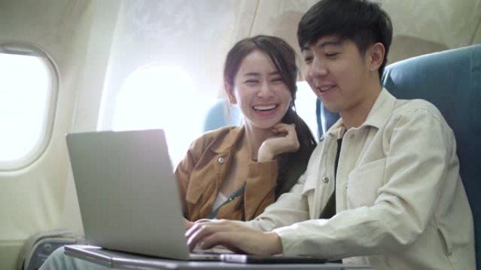甜蜜的夫妇使用笔记本电脑在飞机上娱乐